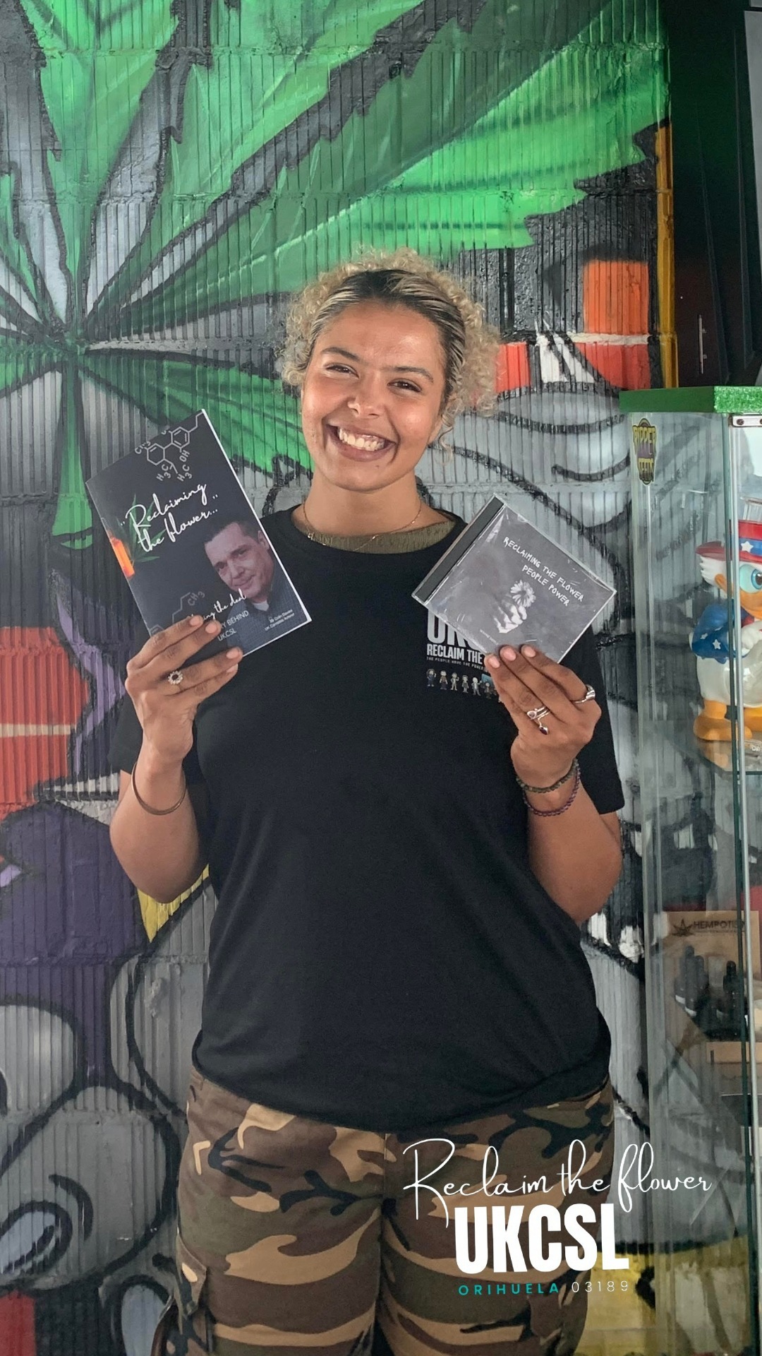 A smiling woman holding the Reclaim the Flower book and CD